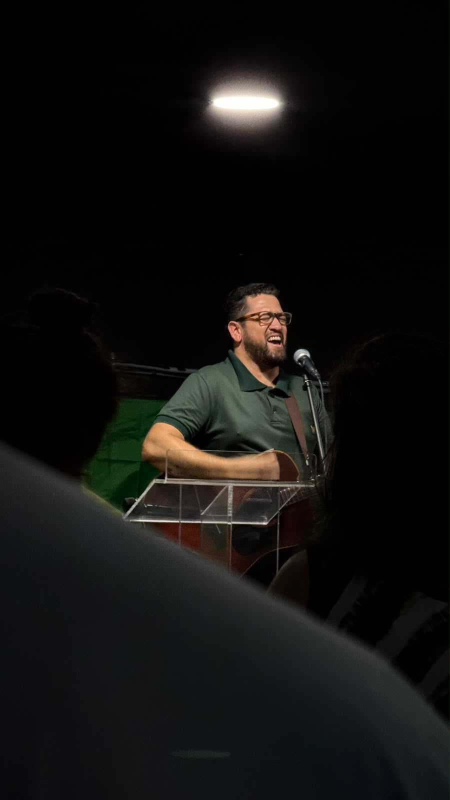 Homem de óculos a cantar e a tocar violão