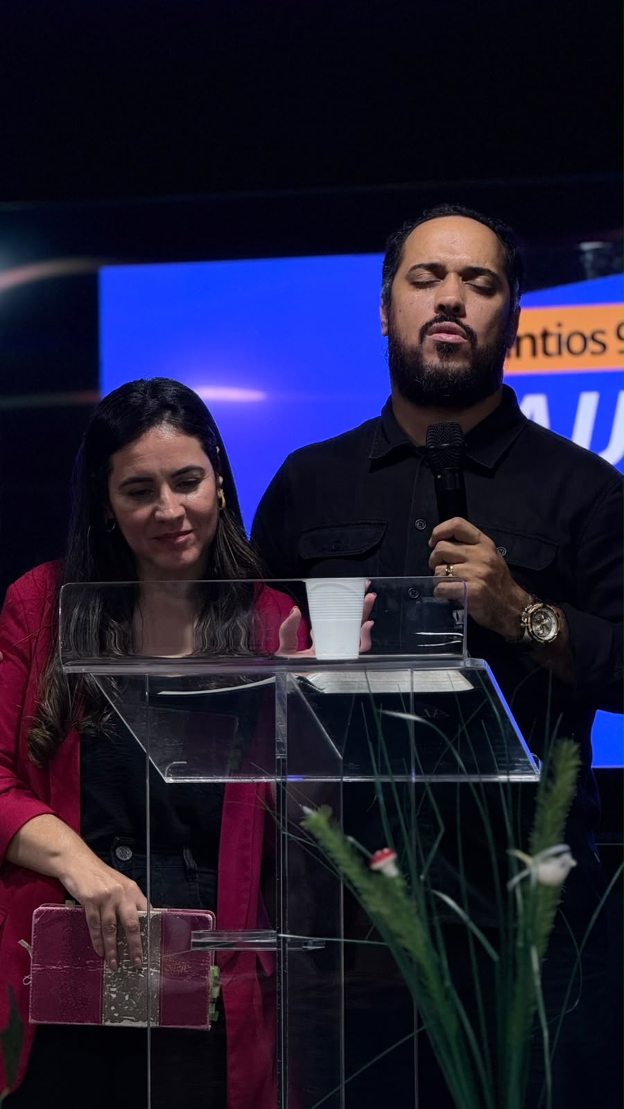 Casal em oração junto ao púlpito de acrílico