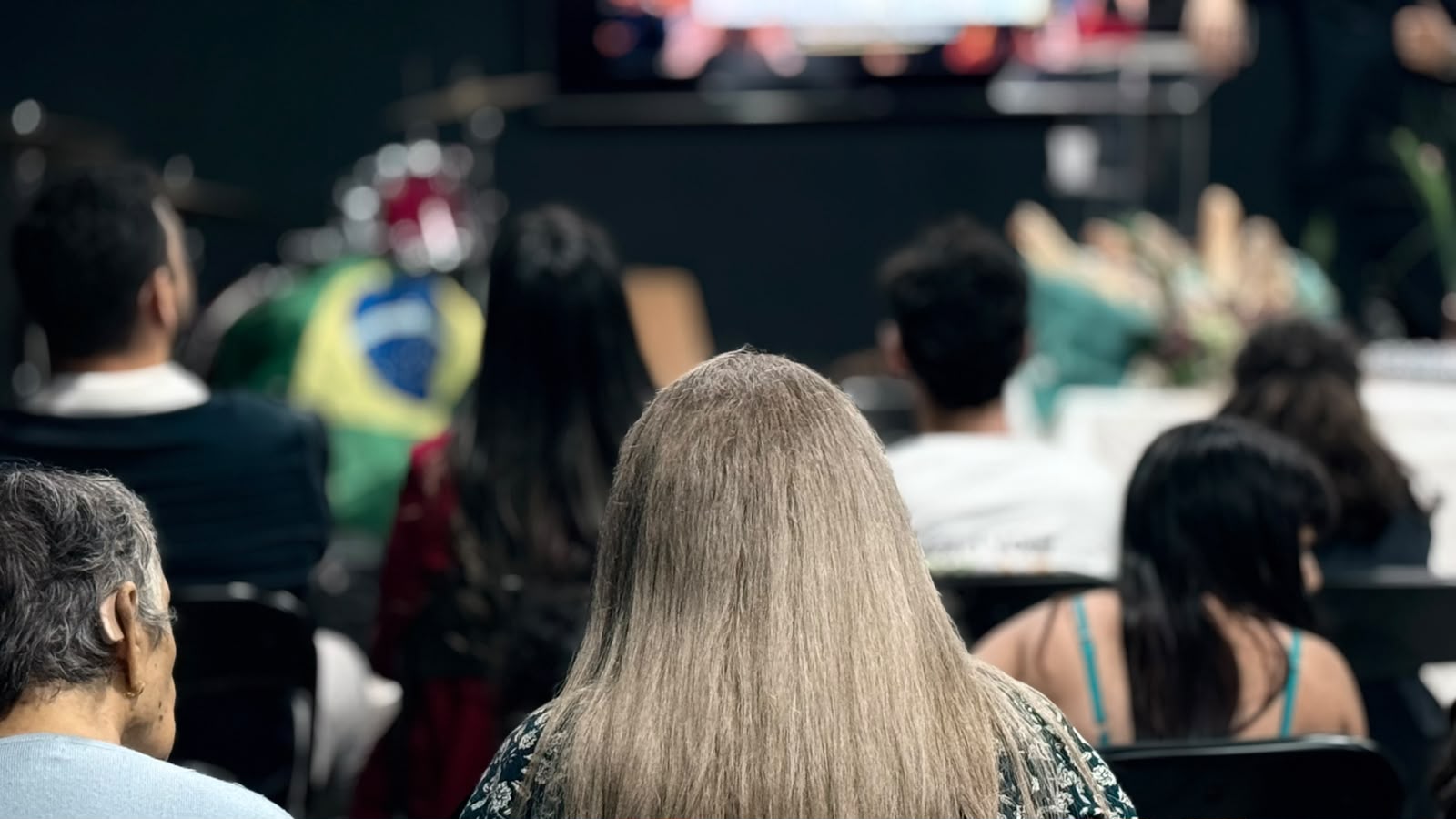 Pessoas sentadas, vistas de costas, durante um culto