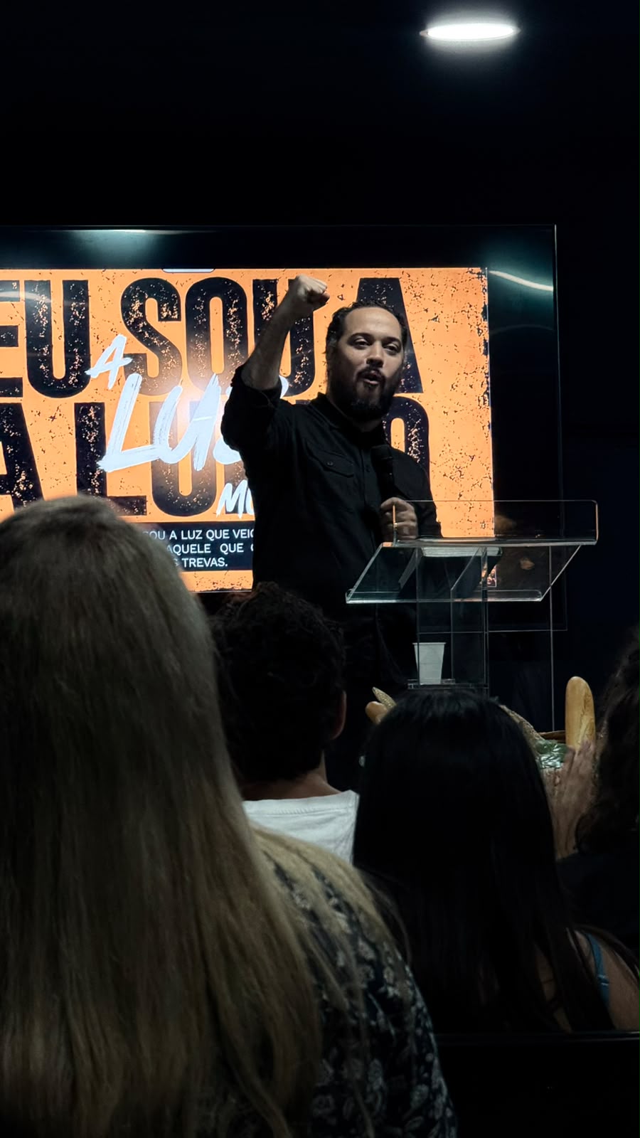 Pregador de punho erguido em frente à igreja, com o tema Eu sou a luz no ecrã